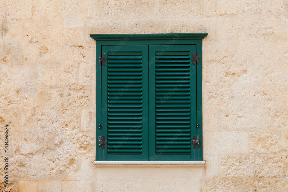 Closed wooden window on the facade of the old Italian home with yellow wall 