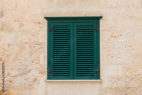 Closed wooden window on the facade of the old Italian home with yellow wall  © Sergey
