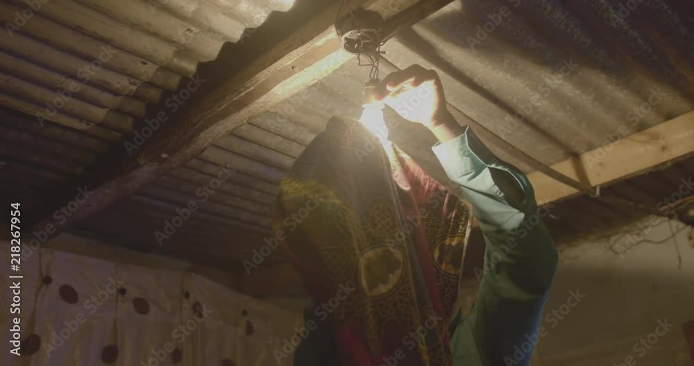 A man fixing his light bulb in his home in the township of Livingstone.