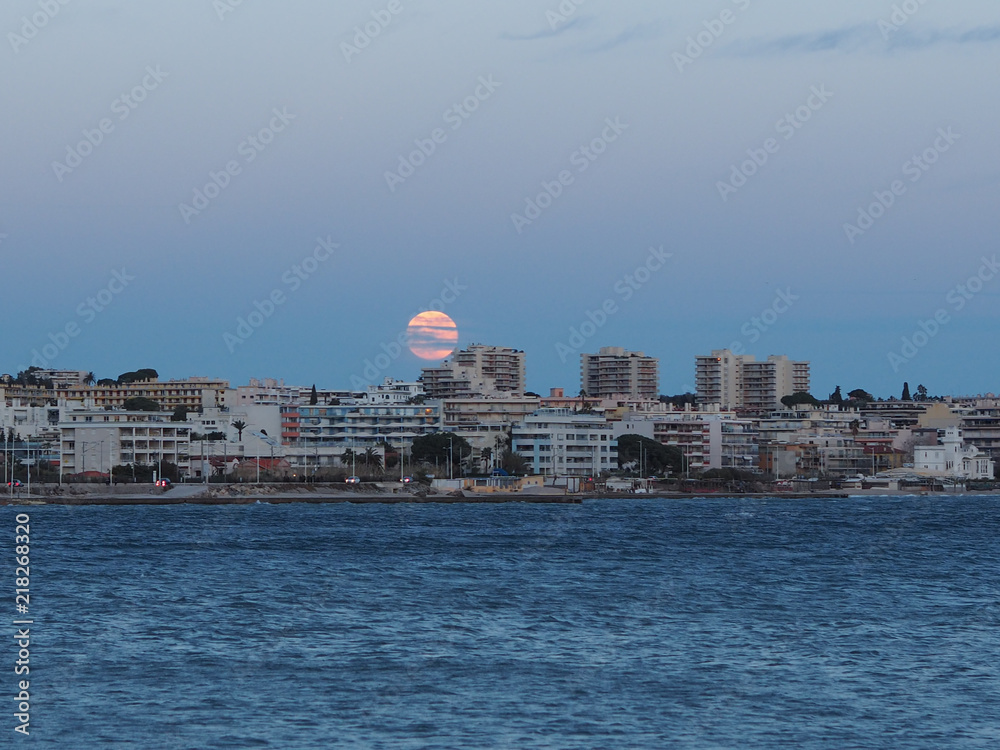 Super Moon hanging above cityscape in French Riviera