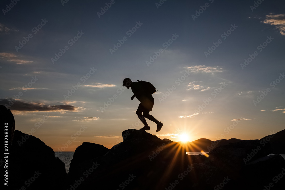 Man jumping on cliffs in sunset