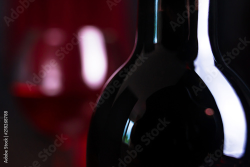 Wine. A glass and a bottle of red wine.. Red wine on a dark background.