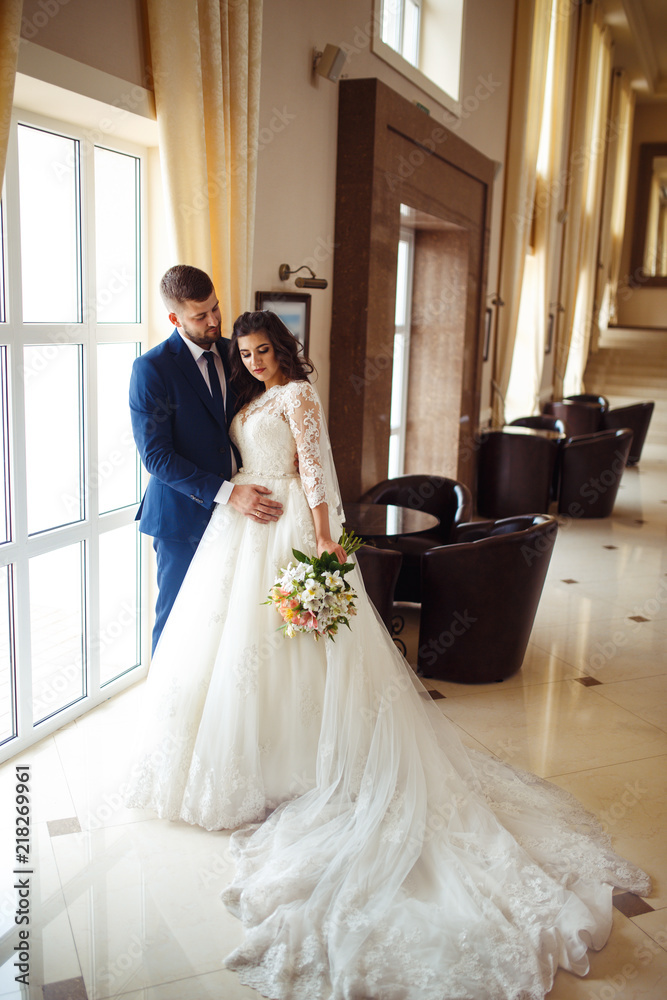 Fototapeta premium Beautiful Bride and Groom enjoy each other in the nice hall of the hotel. happy romantic young couple celebrating their marriage.Sexy kissing stylish couple of lovers close up portrait. wedding