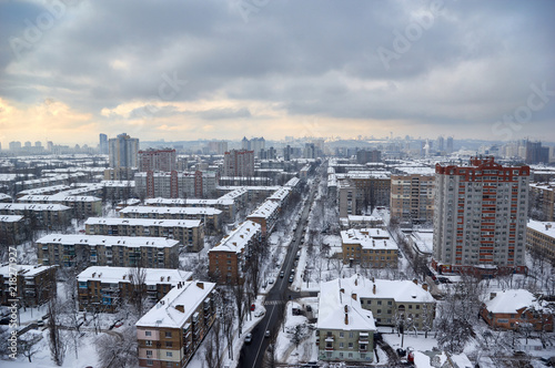 The aerial View of residential district in Kyiv,Ukraine in cloudy winter day.View over the city rooftops with sunlight and snow.Moderns buildings at Industrial uptown, residential neighbourhood