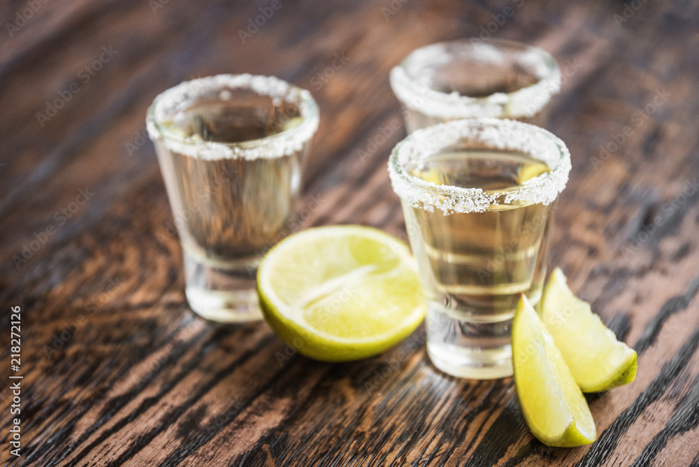 Tequila and lime slices in the defocus on a wooden background in the bar Tequila and lime slices in the defocus on a wooden background in the bar