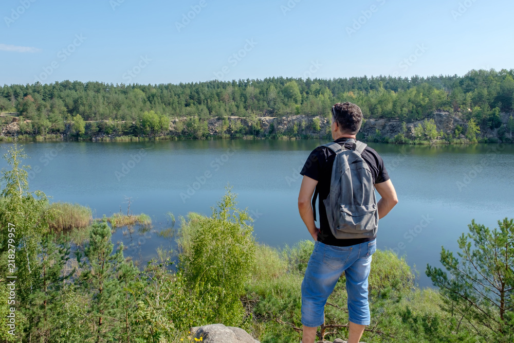 Adult white man with backpack stands on the rock