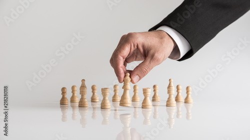 Man in business suit playing chess moving the queen piece lifting it up