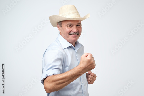 Portrait of handsome successful mature man wearing cowboy hat celebrating his victory holding a fist.
