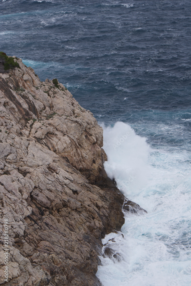 Costa de Cala Rajada en isla de Mallorca, Islas Baleares. Acantilado del mar Mediterráneo con las olas rompiendo en las rocas en día nublado.