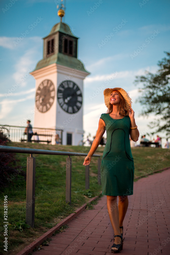 Fototapeta premium Beautiful young woman walking towards the sunset while smiling