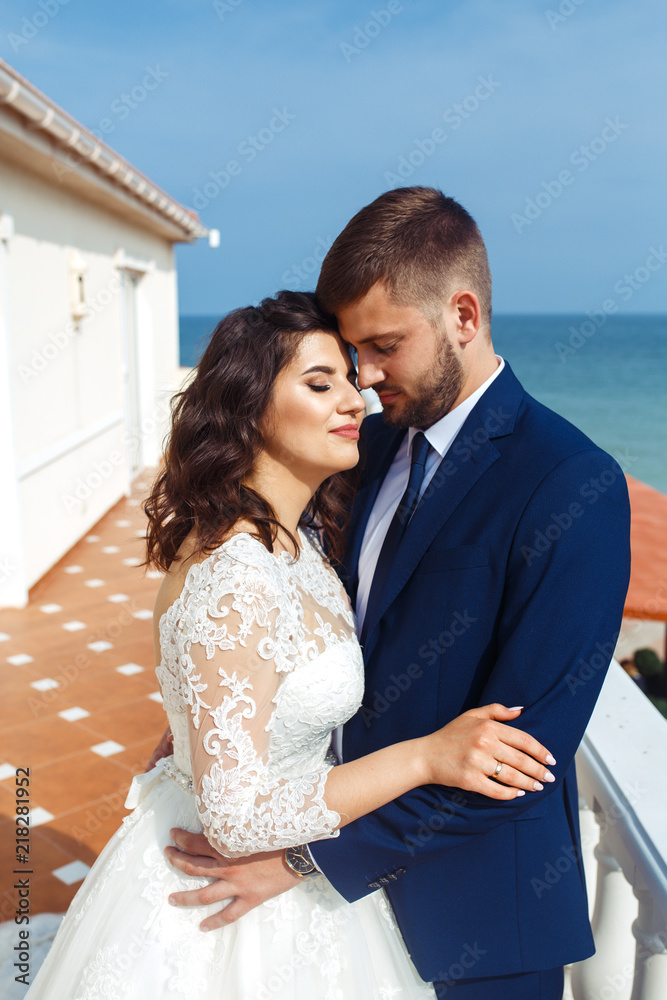 Beautiful Bride and Groom enjoy each other on the background of the ocean. happy romantic young couple celebrating their marriage. Sexy stylish couple of lovers close up portrait. wedding concept.