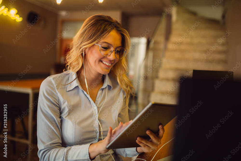 Portrait of beautiful blonde woman with earphones having online call on tablet computer - obrazy, fototapety, plakaty 