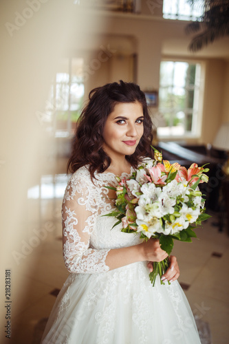 A beautiful bride in a white wedding dress and with a bouquet of flowers enjoying the moment at a beautiful hotel. Great mood, great atmosphere. wedding concept. 
