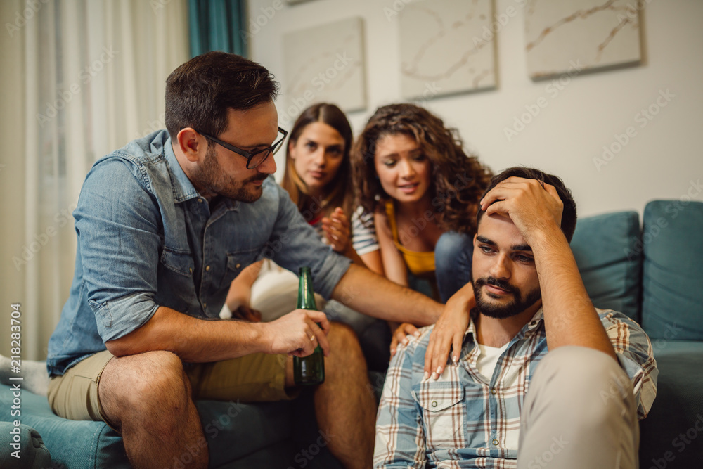 Group of young people comforting their upset friend while discussing problems at home Group of young people comforting their upset friend while discussing problems at home
