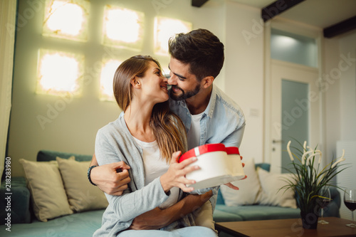 Young woman receiving a surprise gift box from her boyfriend at home. photo