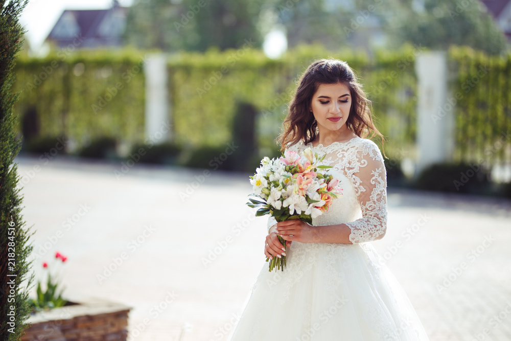 A beautiful bride in a white wedding dress and with a bouquet of flowers enjoying the moment. Wonderful mood, beautiful waves, great atmosphere. wedding concept.