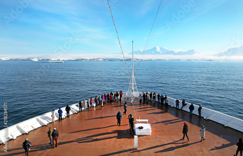 Tourist on Cruise Ship Deck Heading to Anarctic Peninsula, Ice covered Land Ahead