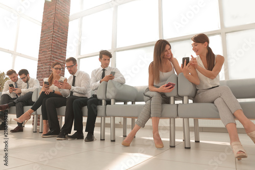 business colleagues using their smartphones sitting in the lobby of the office