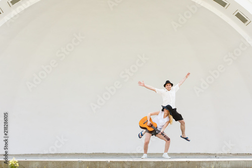 Woman playing guitar, man jumping next to her © Voyagerix