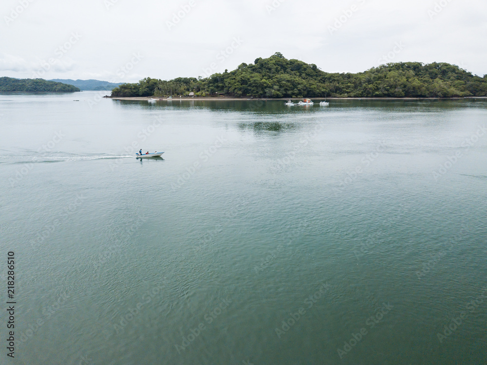 A small motor boat with local fishermen leaves the protected small harbor as they head out into the Gulf of Nicoya Costa Rica in this aerial drone image