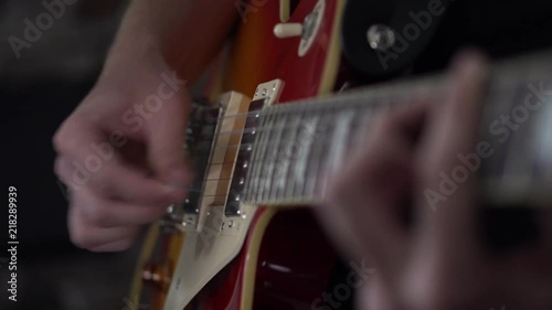 Man quickly strumming power chords on his Les Paul style guitar - close up side shot of his strumming hand photo