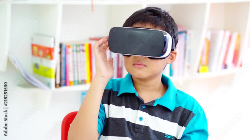 Preteen boy standing in the library while wearing virtual reality goggles. Shot in 4k resolution Preteen boy standing in the library while wearing virtual reality goggles. Shot in 4k resolution