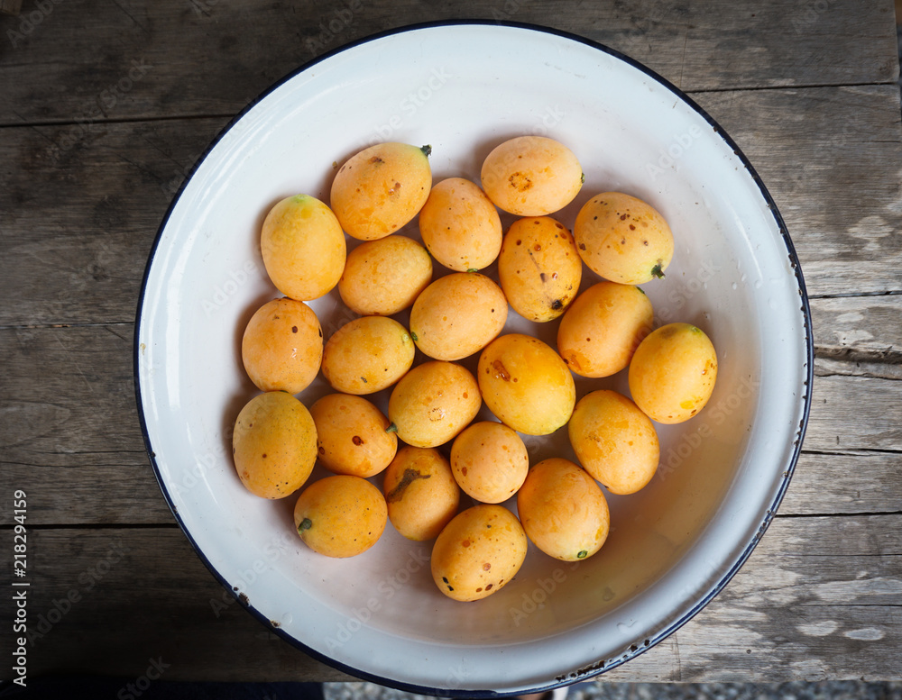 Sweet Marian plum in white bowl on wooden table,tropical fruits