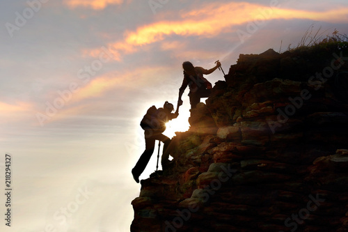 Wallpaper Mural silhouette Young couple  hikers climbing up on the peak of mountain. Climbing ,Helps and Team work concept .  Torontodigital.ca