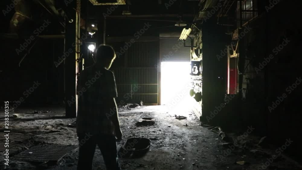 Man walks through filthy hallway towards bright light Man walks through filthy hallway towards bright light