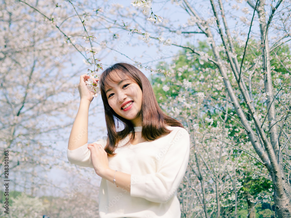 Outdoor portrait of beautiful young Chinese girl smiling among blossom cherry tree brunch in spring garden, beauty, summer, emotion, expression and people concept. Outdoor portrait of beautiful young Chinese girl smiling among blossom cherry tree brunch in spring garden, beauty, summer, emotion, expression and people concept.