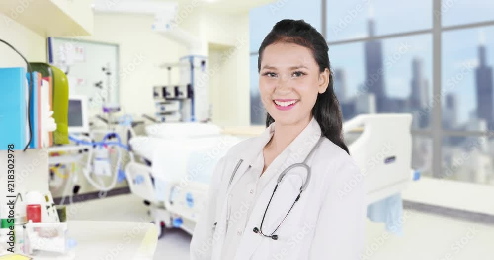 Young female physician standing in the hospital room and smiling at the camera. Shot in 4k resolution Young female physician standing in the hospital room and smiling at the camera. Shot in 4k resolution