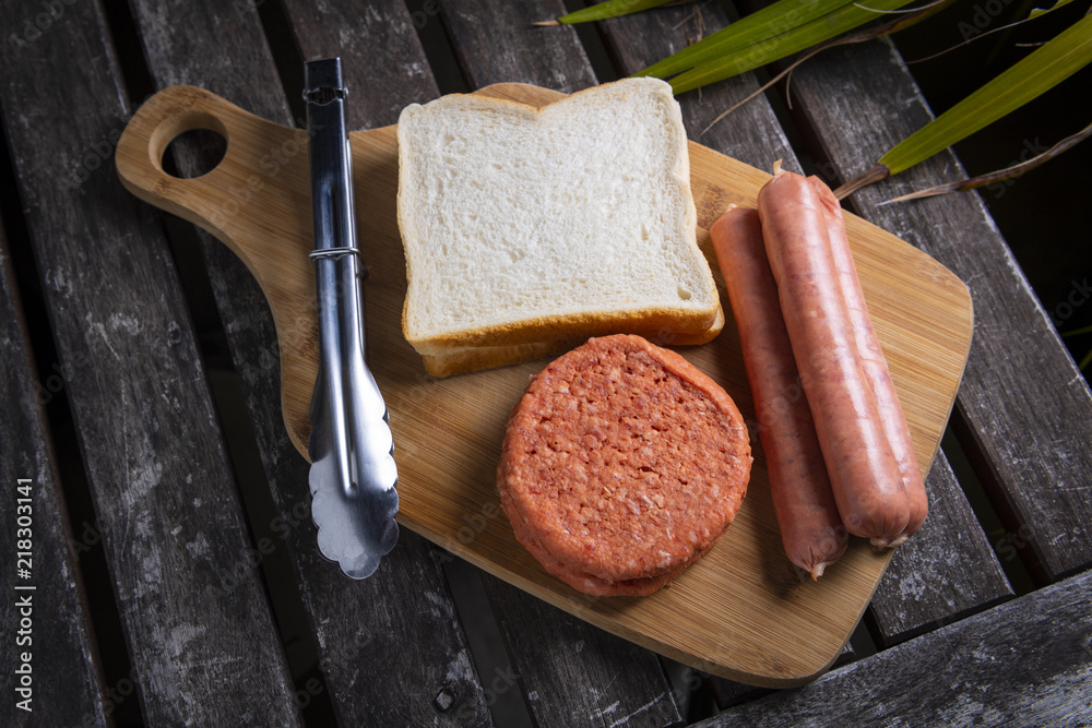 Fototapeta premium Fresh uncooked barbecue sausages, burgers and bread