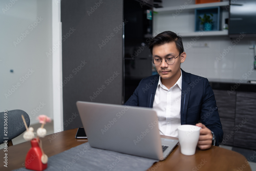 asian malay man working at home with laptop and calculator asian malay man working at home with laptop and calculator