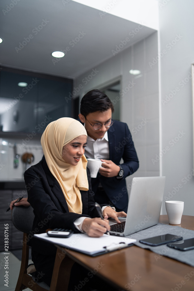 asian malay couple working together at home with laptop and calculator asian malay couple working together at home with laptop and calculator