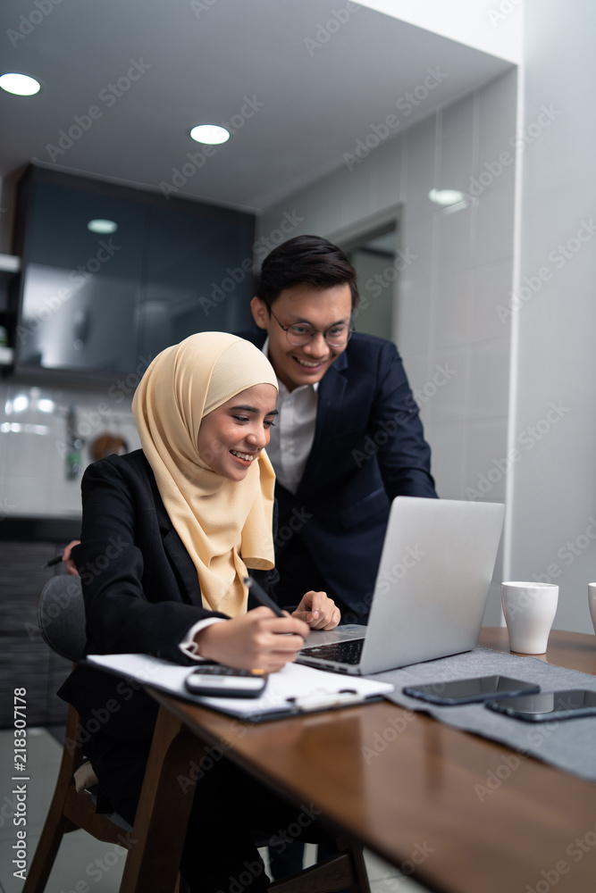 asian malay couple working together at home with laptop and calculator asian malay couple working together at home with laptop and calculator