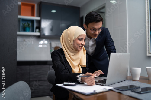 asian malay couple working together at home with laptop and calculator