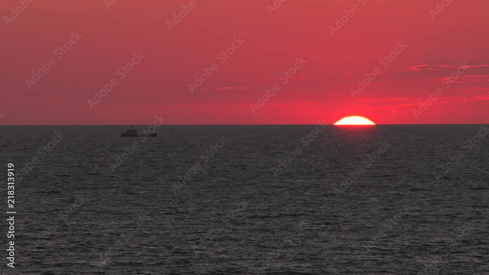 Red sunset. The sun touches the horizon. Calm sea. Small waves. 4K, UHD, 50p,60p,Panning,Closeup, Red sunset. The sun touches the horizon. Calm sea. Small waves. 4K, UHD, 50p,60p,Panning,Closeup,
