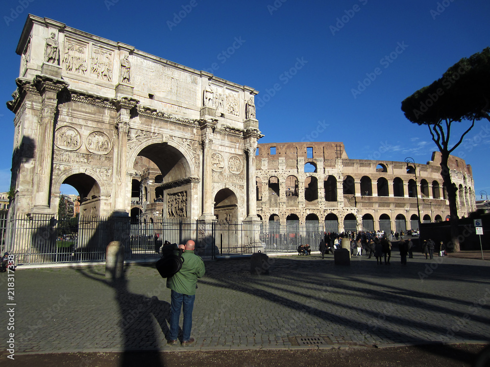 man stops to appreciate the Arch of Constantine next to the Colosseum in Romeancient,arch,architecture,art,attraction,building,coliseum,colosseum,constantine,daytime,empire,europe,famous,historical,hi