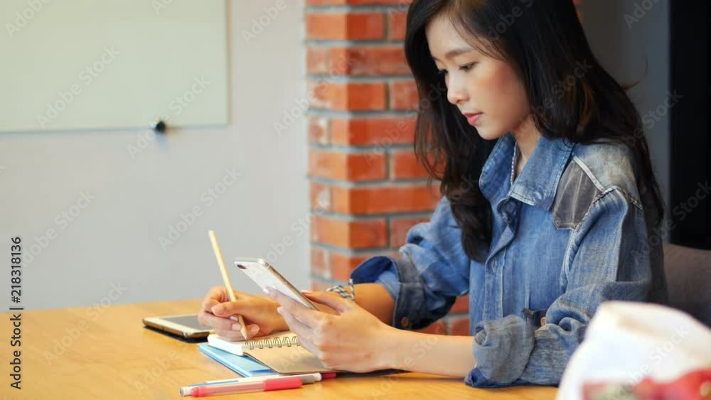 Businesswoman owners using app smartphone and take notes in office. Asian girl texting on smartphone in office. Businesswoman owners using app smartphone and take notes in office. Asian girl texting on smartphone in office.