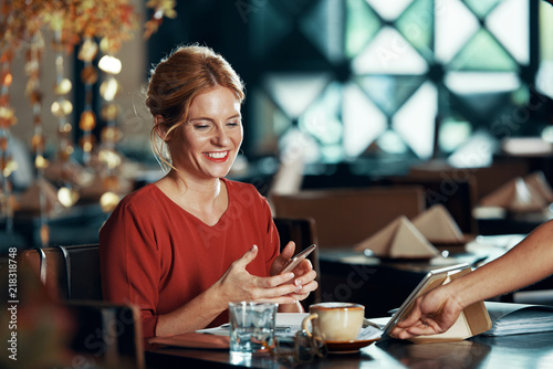 Waiter bringing cup of coffee to beautiful smiling woman in restaurant