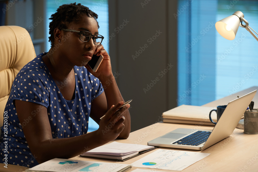 Serious businesswoman in glasses talking to client on the phone Serious businesswoman in glasses talking to client on the phone