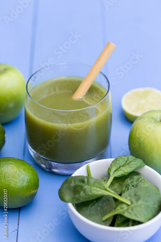 Healthy green smoothie drink with straw blue table background