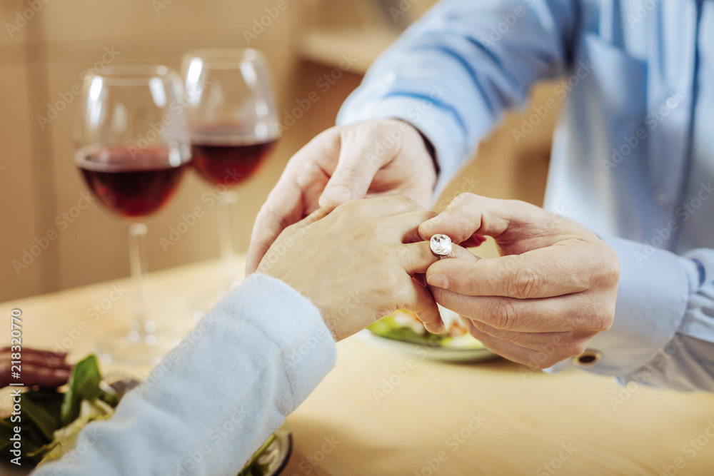 Obraz premium Shining crystal. Excited serious man wearing a ring to a woman while making a proposal