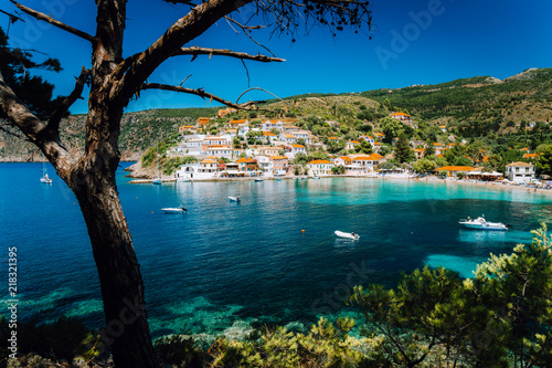 Assos village, Kefalonia Greece. View on turquoise transparent bay lagoon of Mediterranean sea. Surrounded by green pine trees. Blue deep pattern on bottom