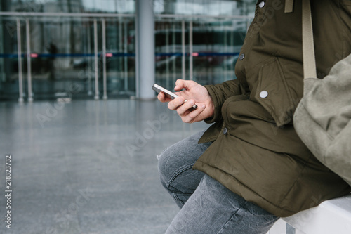 A young male tourist at the airport or near a shopping center or station calls a taxi or talks on a cell phone or communicates with friends using a mobile phone. photo