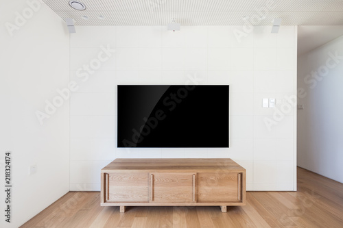 television with wood shelf in a white interior.