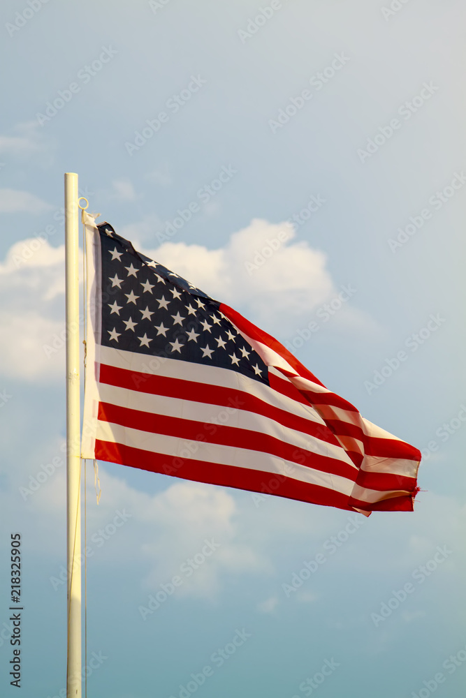 Obraz premium American flag on a blue sky with clouds background