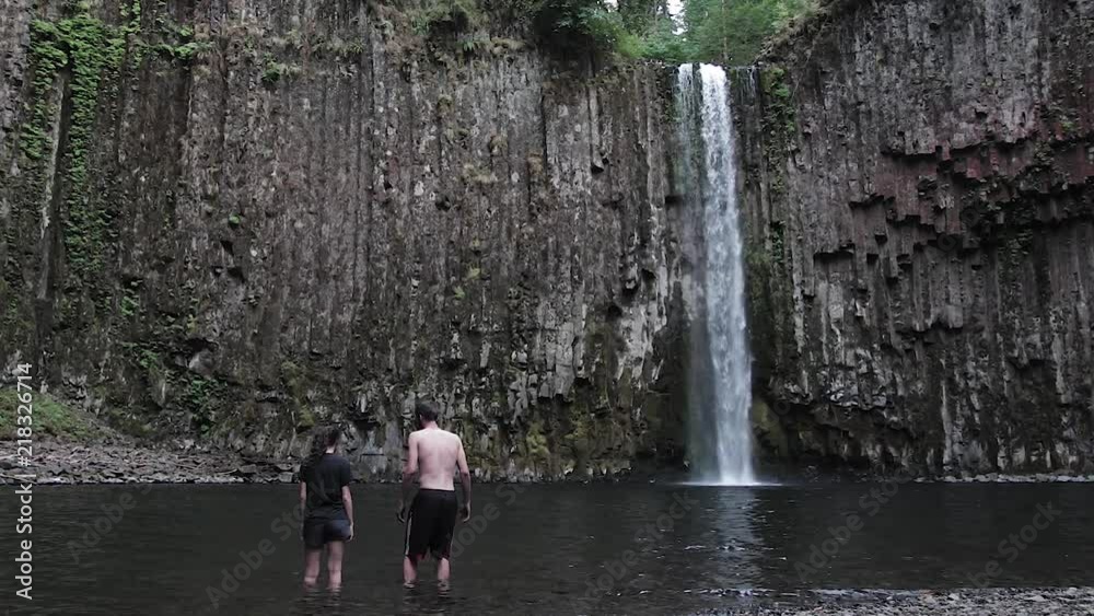 Couple standing in front of beautiful Abiqua Falls waterfall in Oregon slow motion Couple standing in front of beautiful Abiqua Falls waterfall in Oregon slow motion