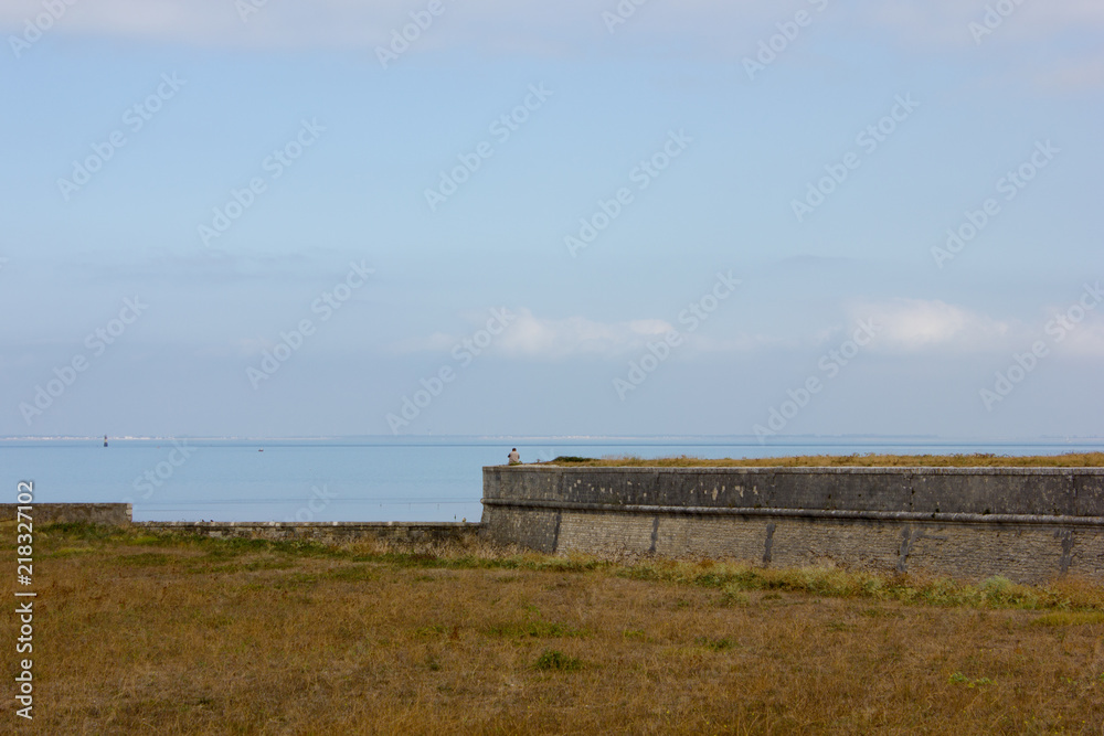 Man sitting at Fortress of Vauban by the sea, France