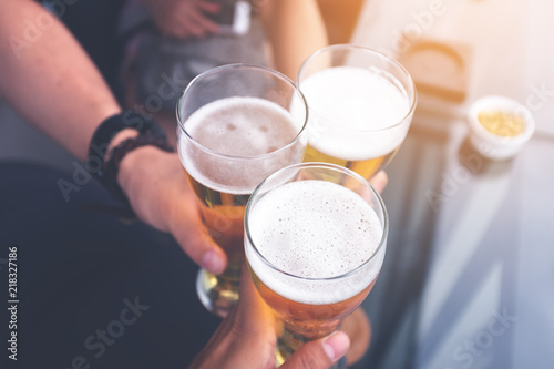 people, men, leisure, friendship and celebration concept - The group of people drinking beer and clinking glasses on rooftop bar for celebration